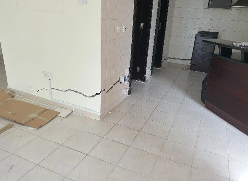 Diagonal crack running along the base of a tiled interior wall