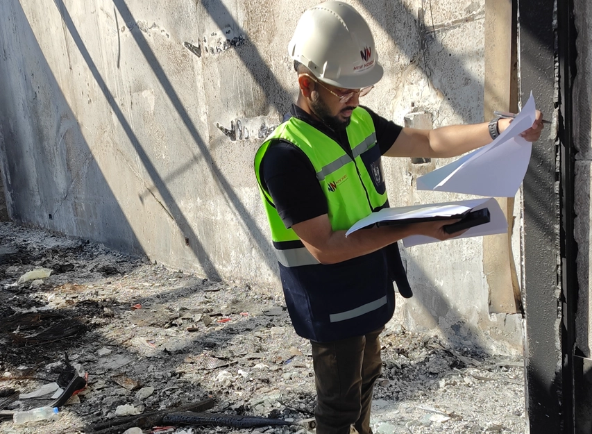 New Nordic engineer reviewing documents among soot-covered walls and fire debris