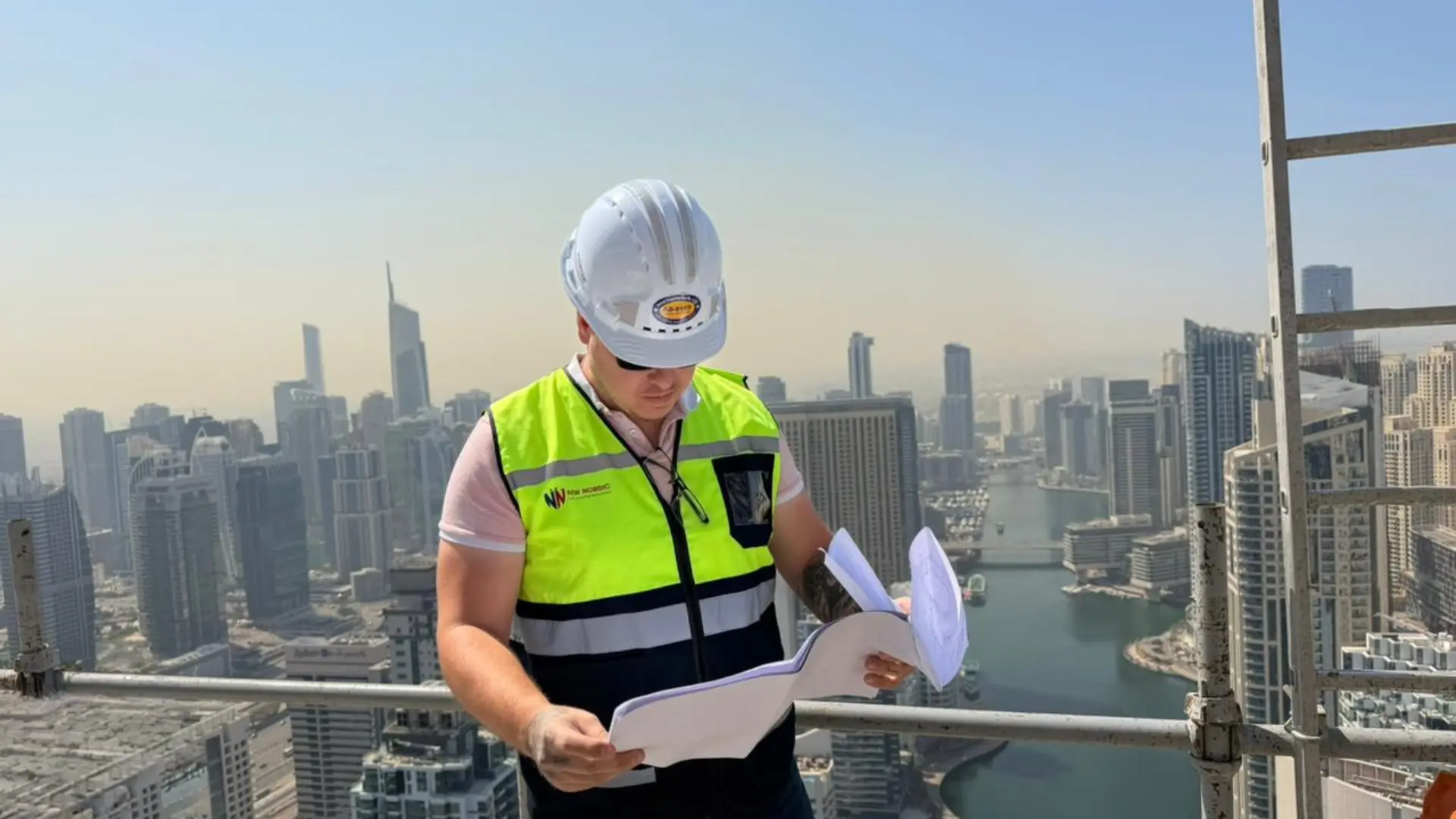 New Nordic engineer reviewing drawings on a high-rise rooftop above the Dubai skyline
