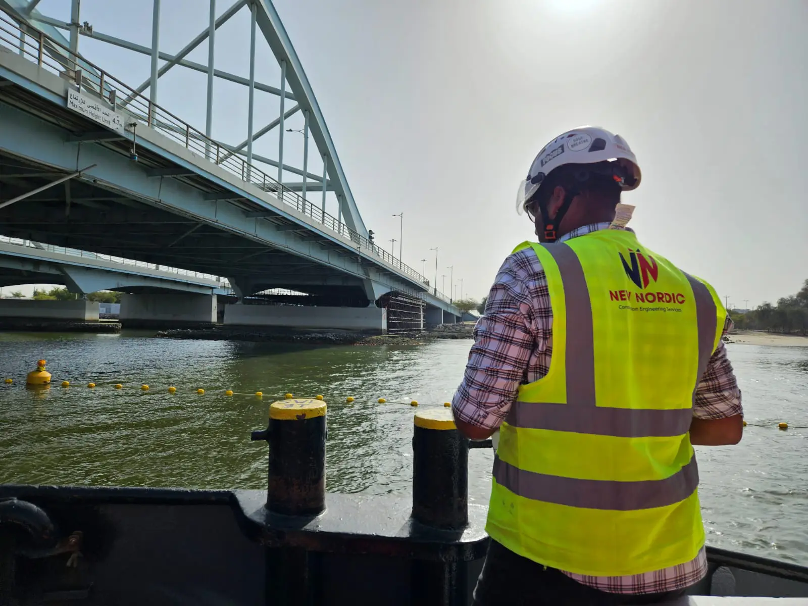 New Nordic engineer aboard a boat inspecting an arch bridge over a waterway