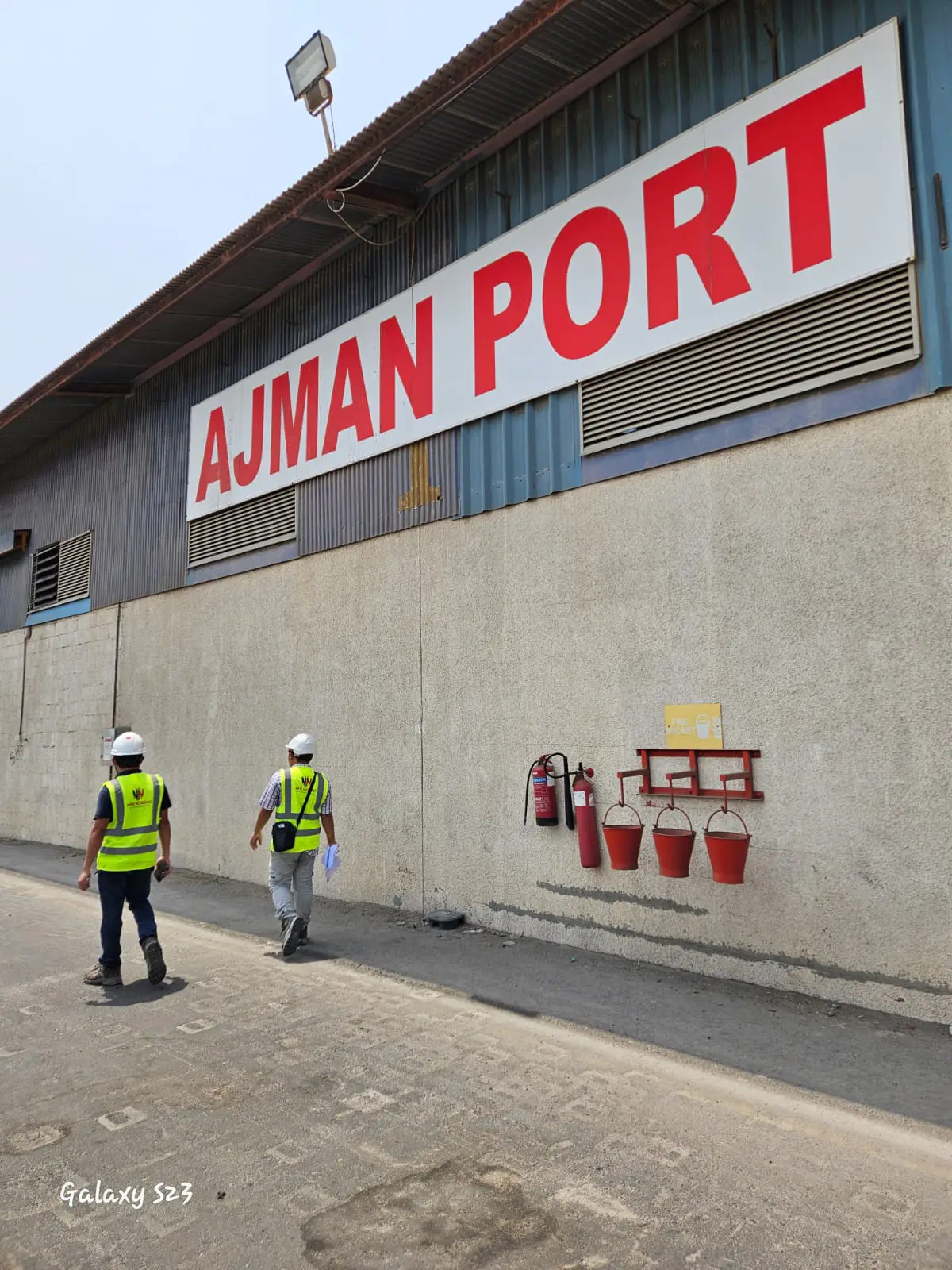 New Nordic engineers walking past a warehouse building at Ajman Port during a site inspection