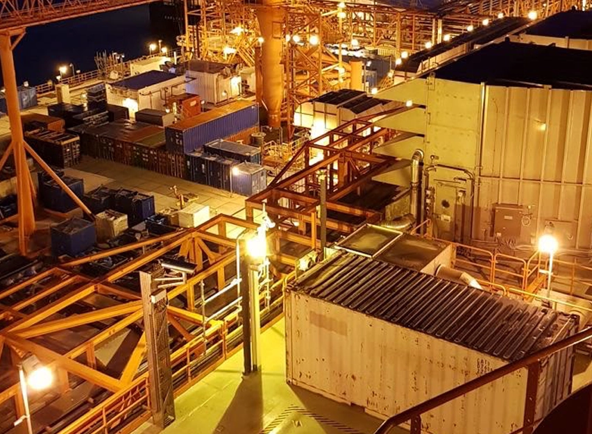 Night view of an industrial facility with shipping containers and conveyor gantries