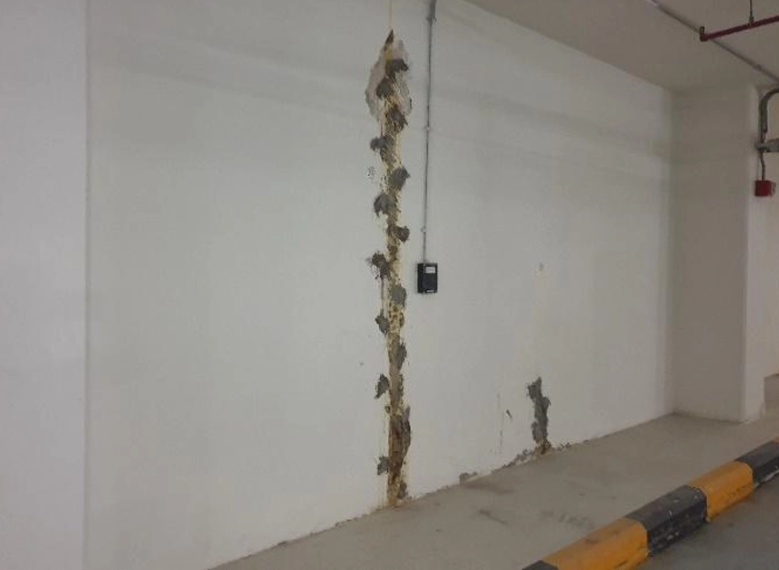 Water staining and efflorescence running down a parking garage wall