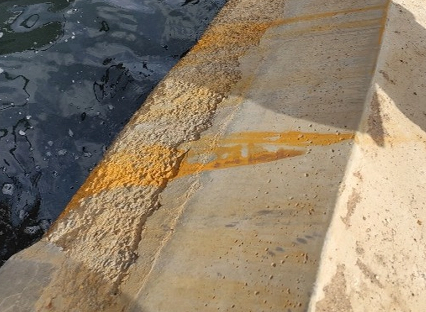 Rust staining running across the concrete face of a quay wall at the waterline
