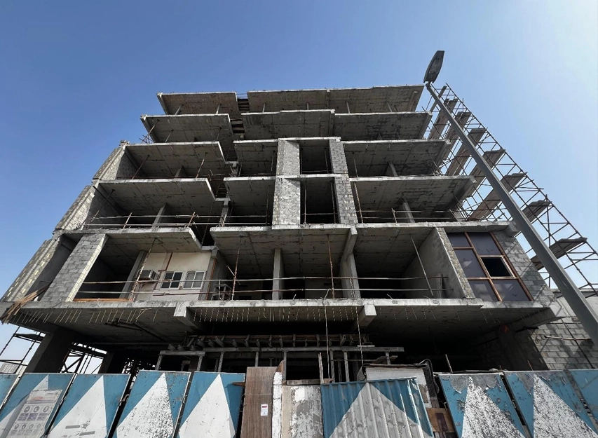 Multi-storey concrete building under construction with scaffolding