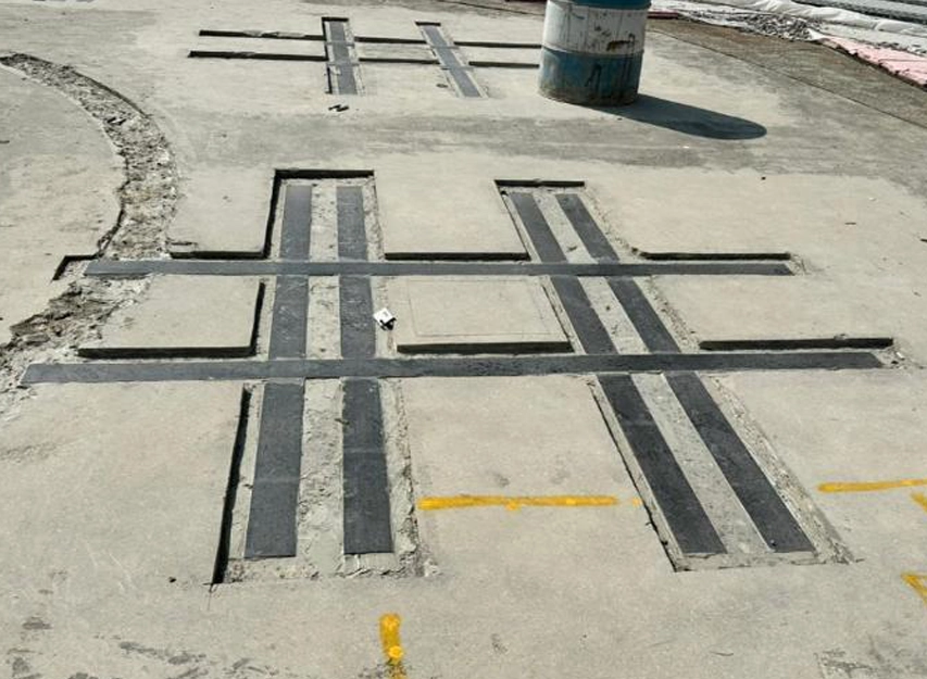 Concrete pavement with repaired joints forming a sealant grid near a manhole